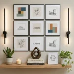 Modern gallery wall display with a 3x3 grid of framed art prints flanked by sleek black wall sconces above a floating wooden shelf with potted plants and decorative objects.